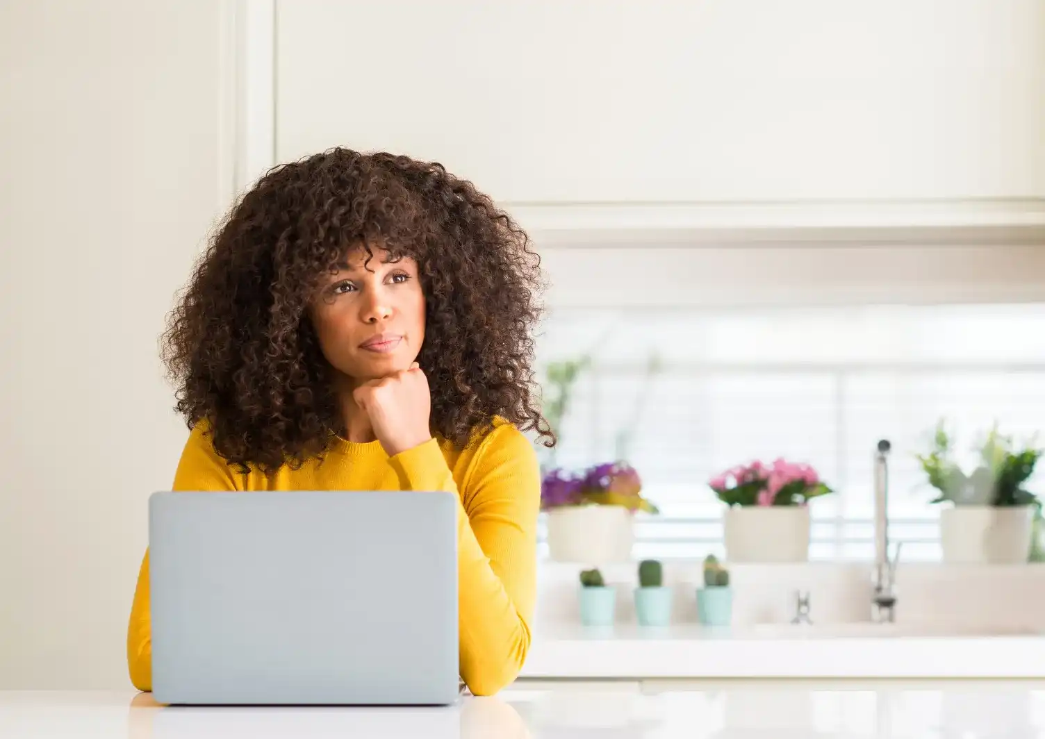 Vos questions sur BeMum : une femme pensive devant son ordinateur portable dans sa cuisine